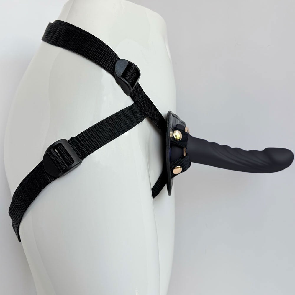 Nexus Fun and Love harness kit with adjustable black strap on harness and black tease silicone dildo, with dildo inserted into the harness and harness on a mannequin, angled from the side to show how harnes wraps aroound sides and back