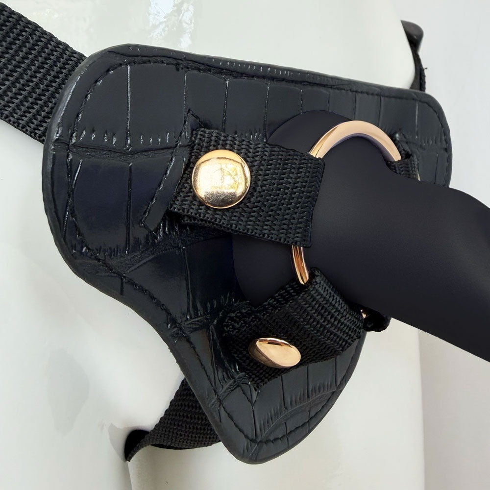 Nexus Fun and Love harness kit with adjustable black strap on harness and black tease silicone dildo, with dildo inserted into the harness zoomed into the base  of the Tease in the gold included oring